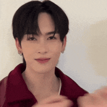 a young man in a red shirt is making a heart shape with his hands