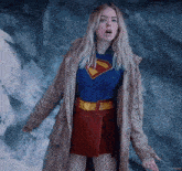 a woman in a superman costume is wearing a coat