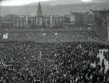a large crowd of people are gathered in front of a building with a clock tower on top