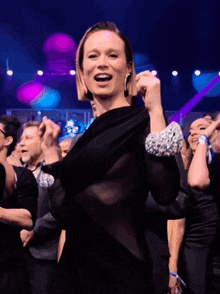 a woman in a sheer black dress is dancing in a crowd of people