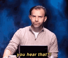 a man sitting in front of a laptop says " you hear that ? "