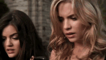 two women are standing next to each other and one of them is looking at her phone .