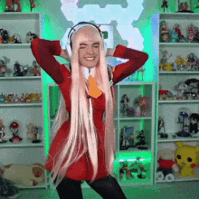 a woman wearing headphones and a pink wig is dancing in front of a shelf full of figurines .