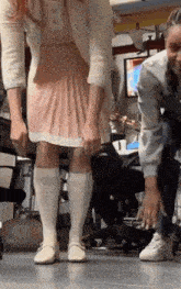 a woman in a pink dress and white socks is standing next to a man