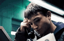 a young man is talking on a telephone while looking at a piece of paper