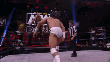 two men are wrestling in a wrestling ring while a referee watches