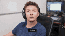 a man wearing headphones is sitting in front of a computer and says hotdog