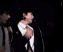 a man in a white shirt and black tie holds a microphone in his hand
