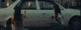 a woman is spraying paint on a car 's side .
