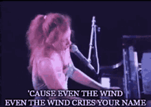 a woman is singing into a microphone while playing a piano and singing a song .