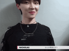 a young man wearing a black sweater and a necklace with the name nicholas on it