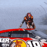 a man is standing on top of a race car sponsored by bass pro