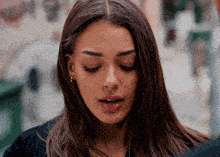 a woman with her eyes closed looks down at something