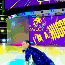 a woman in a blue dress is standing in front of a large screen that says i 'm a huge .