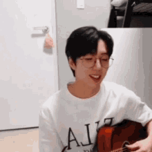 a young man wearing glasses is playing a guitar in a living room .