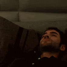 a man with a beard is standing in a dark room looking at the camera .