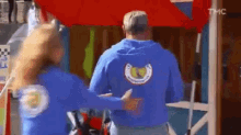 a man in a blue hoodie is hugging a woman in a blue hoodie .
