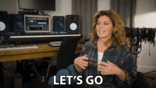 a woman in a plaid shirt says let 's go in front of a keyboard