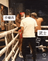 a man in a white shirt is standing in a boxing ring with chinese writing on it