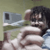 a man wearing glasses is holding a bunch of money in his hands .