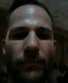 a close up of a man 's face with a beard looking at the camera