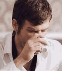 a man in a white shirt is holding a napkin to his nose .