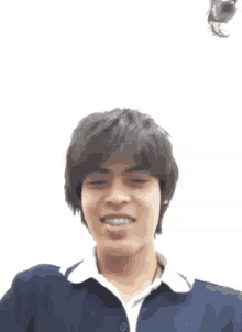 a young man with braces on his teeth smiles in front of a bird