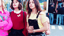 three women are standing next to each other on the street .
