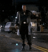 a man is dancing on the street in front of a store that says ' pop shop ' on it
