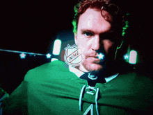 a man wearing a green jersey with the nhl logo on his face