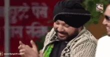 a man wearing a turban is laughing with another man in front of a sign that says sony