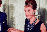 a woman wearing a necklace and earrings is holding a sword in her mouth .