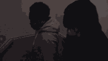a man in a hoodie is standing in a dark parking lot holding a microphone .