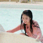 a young girl in a pink shirt is playing in a pool .