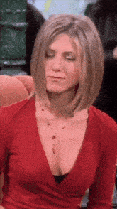 a woman wearing a red top and a necklace is sitting with her eyes closed