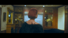 a woman with red hair is wearing a black feathered coat