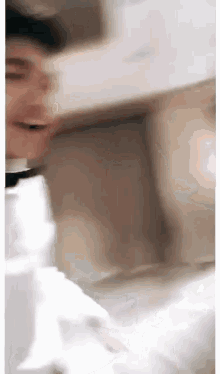 a blurry picture of a person laying on a bed with a white shirt on .