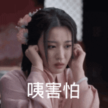a woman with a flower in her hair covering her ears