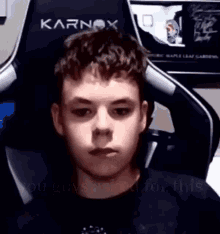 a young man is sitting in a gaming chair and making a funny face .