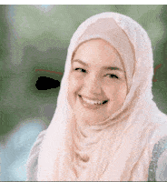 a woman wearing a hijab is smiling at the camera