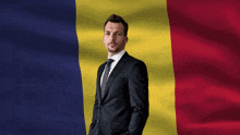a man in a suit and tie wearing sunglasses stands in front of a romania flag