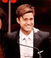 a man in a suit and tie is smiling at a microphone