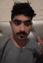a man with a mustache is wearing a grey shirt with a zipper