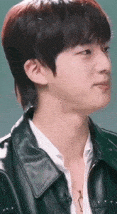 a close up of a person wearing a leather jacket and a necklace .