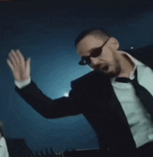 a man wearing sunglasses and a suit is dancing
