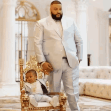 a man in a purple suit is standing next to a baby on a purple throne .