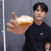 a man wearing a black nike polo shirt is holding a donut