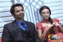 a man in a suit and a woman in a red dress sit next to each other