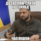 a man is sitting at a desk looking at his phone with a foreign language caption above him