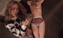 a woman is laying on a bed next to a little girl wearing underwear .
